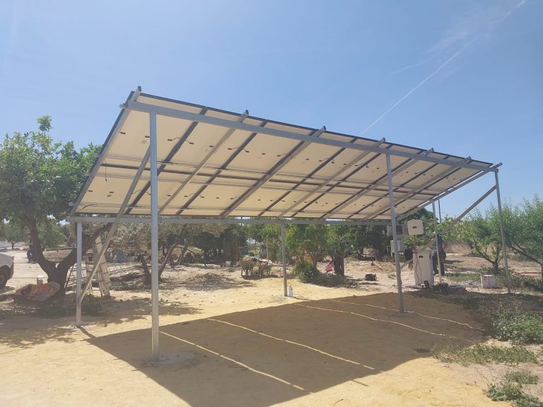 Estructura metálica con techo de lona blanca en un área al aire libre y vegetación alrededor.