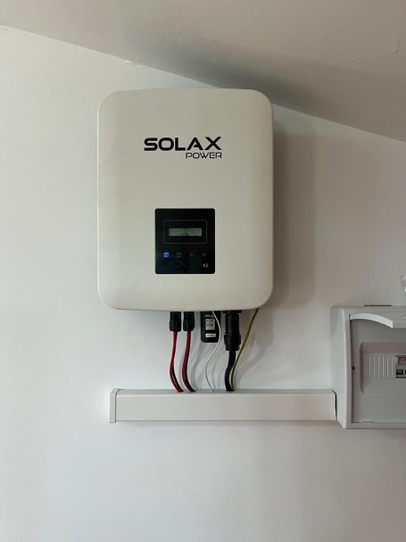 Inversor solar de la marca Solax montado en la pared, con conexiones visibles.