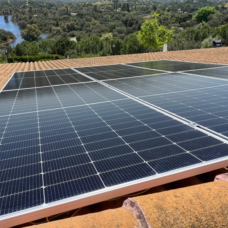 Paneles solares instalados en una azotea con vista a un lago.